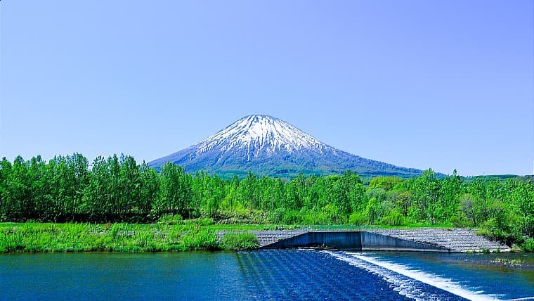 北海道蘭越町の尻別川：清流日本一に何度も輝いた美しい川。ニセコ連峰を背景に、カヌーや釣りなどのアクティビティが楽しめます。