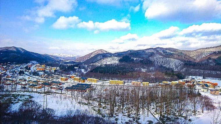 北海道西興部村の風景：オレンジの壁と緑の屋根で統一された美しい街並みと、面積の約9割を占める広大な森林が広がる風景です。